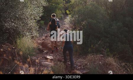 Les gens marchent un chemin rocheux en montée à travers une végétation luxuriante et sèche Banque D'Images