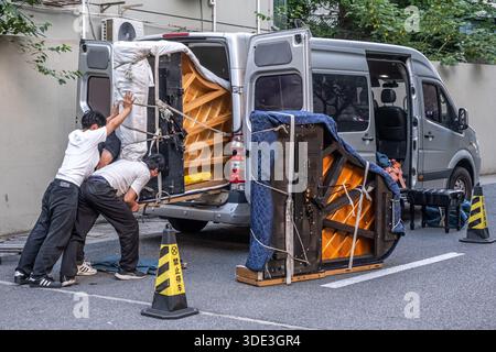 Shanghai, Chine - 17 mai 2025 trois hommes asiatiques chargeant une camionnette avec de grands pianos. Banque D'Images
