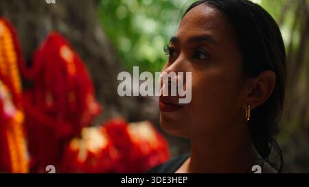 Jeune femme levant les yeux, contemplant les offrandes spirituelles dans le cadre de la nature du temple Banque D'Images