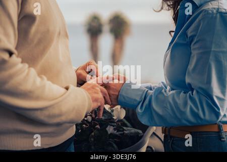 Gros plan d'un couple d'âge moyen tenant la main sur une terrasse, geste intime exprimant la confiance et le lien émotionnel. Banque D'Images