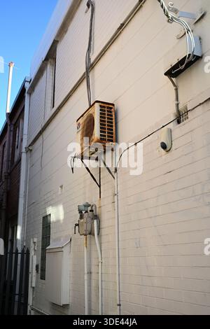 Rouille Chunlan climatiseur monté sur un mur de briques blanches peintes, sur le côté d'un bâtiment Banque D'Images