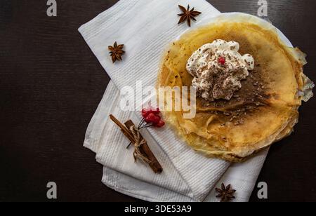 Crêpes fines avec crème fouettée et épices sur la serviette vue de dessus Banque D'Images