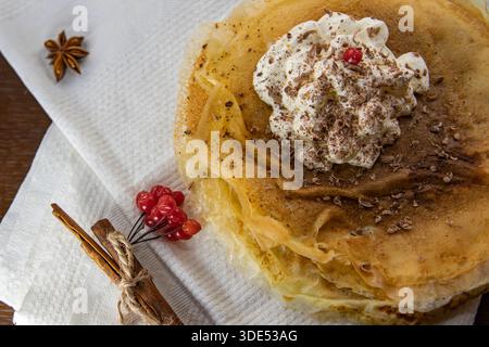 Crêpes fines avec crème fouettée et épices sur la serviette vue de dessus Banque D'Images