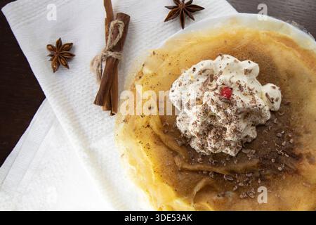 Crêpes fines avec crème fouettée et épices sur la serviette vue de dessus Banque D'Images