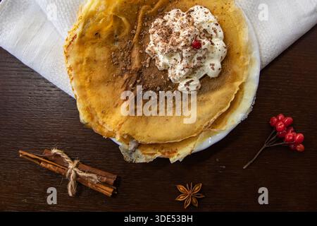 Crêpes fines avec crème fouettée et épices sur la serviette vue de dessus Banque D'Images