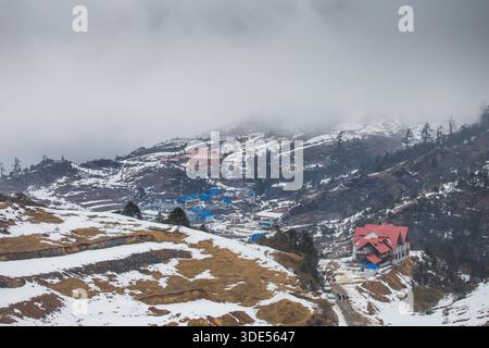 Village enneigé niché dans une colline himalayenne Banque D'Images