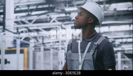 Ingénieur industriel se promenant dans l'usine moderne et inspectant les lignes de production automatisées et les équipements robotiques, surveillant l'efficacité du flux de travail et les processus de fabrication intelligents. Banque D'Images