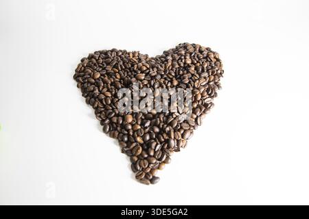 Riches grains de café brun disposés en forme de cœur, créant une composition confortable et accueillante parfaite pour le café, le café, la romance et les visuels de style de vie. Banque D'Images