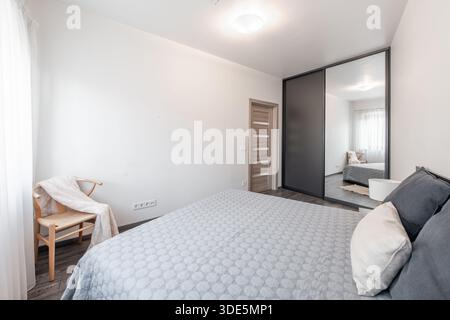 Cette chambre moderne bien éclairée dispose d''un élégant placard à miroirs, d''un mobilier élégant et d''un intérieur apaisant. Banque D'Images