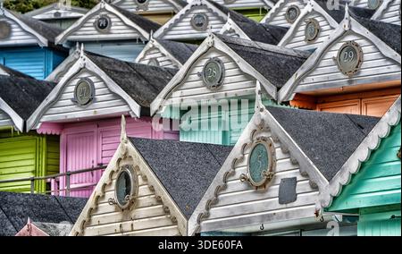 Alice Beach Huts - vue rapprochée des toits et des sections supérieures de plusieurs cabanes de plage peintes de couleurs vives, Walton-on-the-Naze, Essex, Angleterre, Royaume-Uni. Banque D'Images