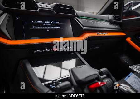 Vue intérieure rapprochée d'une Lamborghini Urus se Orange dans un atelier. Évents hexagonaux, appareillage de commutation angulaire, script Lamborghini et invite russe sur scr Banque D'Images
