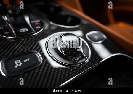 Le gros plan montre le bouton marche/arrêt moleté chromé, le sélecteur de mode d'entraînement, le système antipatinage DÉSACTIVÉ, le système d'arrêt automatique DÉSACTIVÉ, le frein de stationnement et les porte-gobelets en brun Banque D'Images