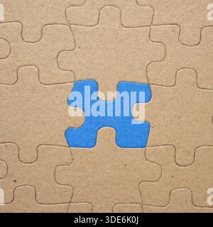 Gros plan d'un puzzle marron avec une pièce bleue. Symbolisant l'individualité, le leadership, l'unicité ou se démarquant de la foule. Concept de un Banque D'Images