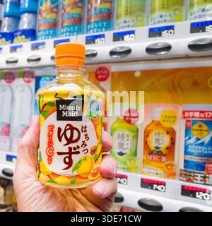 Les distributeurs automatiques omniprésents au Japon offrent une large gamme de boissons rafraîchissantes, comme en témoigne cette sélection dans le quartier Sakyo de Kyoto. Une main tient un b. Banque D'Images