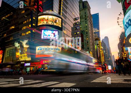 New York, États-Unis, 21 juillet 2011 : Times Square montre le flou de mouvement de la circulation et des piétons contre les panneaux d'affichage vibrants et les lumières de la ville au soleil Banque D'Images