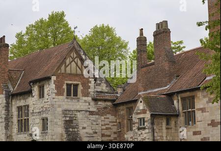 Yorkshire en Angleterre : vieux bâtiment en pierre et briques avec toit de tuiles rouges et de hautes cheminées entourées d'arbres verts sous un ciel couvert Banque D'Images