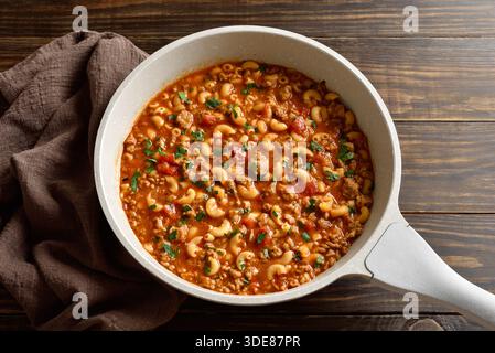 Goulash américain, plat avec bœuf haché, légumes et pâtes en sauce tomate dans une poêle de cuisson sur une table en bois. Vue rapprochée Banque D'Images