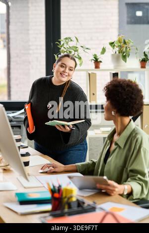 Deux femmes gestionnaires s'engagent dans une discussion créative tout en travaillant à leur bureau. Banque D'Images