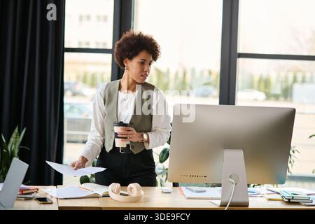 Responsable féminin bouclé s'engageant dans le travail dans un cadre de bureau lumineux et élégant. Banque D'Images