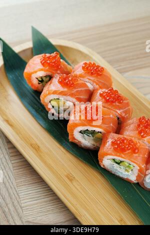 Les rouleaux de sushi lumineux sont soigneusement disposés sur un plateau en bois. Ces rouleaux comportent du saumon, de l'avocat et des garnitures, soulignant les couleurs vibrantes du Banque D'Images
