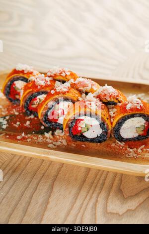 Des rouleaux de sushi fraîchement préparés sont disposés soigneusement sur un plateau en bois. Les rouleaux contiennent des ingrédients vibrants tels que le poisson, les légumes et le riz. Parfait fo Banque D'Images