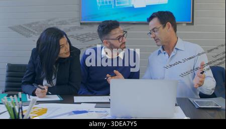 Discuter des collègues dans la salle de réunion, en chemise habillée, chandail bleu marine, blazer, revoir les plans d'ordinateur portable Banque D'Images