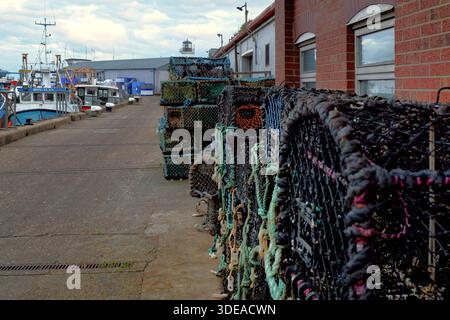 Casiers à homard empilés sur le quai à côté des bateaux de pêche dans le port de Scarborough, North Yorkshire, Angleterre, Royaume-Uni Banque D'Images