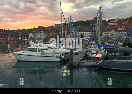 Yachts amarrés dans le port de Scarborough au coucher du soleil, avec le front de mer de la ville formant une toile de fond pittoresque sous un ciel nocturne spectaculaire - Yorkshire, Royaume-Uni Banque D'Images
