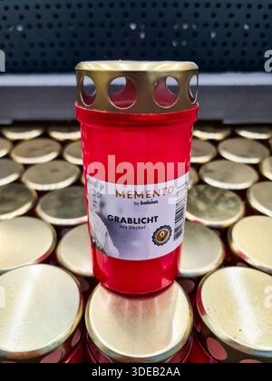 Kiel, Allemagne - 22. Décembre 2025 : lumière funéraire rouge avec couvercle doré debout sur un affichage de bougies similaires Banque D'Images