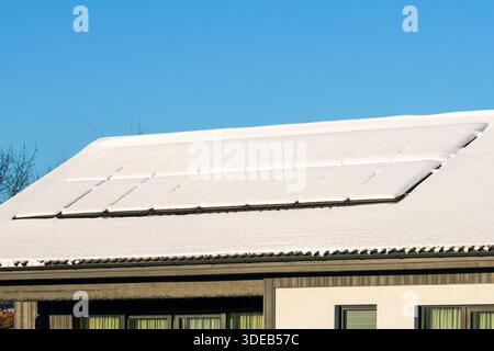 Panneaux solaires recouverts de neige fraîche sur le toit d'une maison moderne, mettant en évidence les défis hivernaux pour la production d'énergie renouvelable Banque D'Images