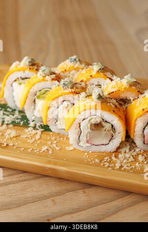Les rouleaux de sushi colorés disposés soigneusement sur un plateau en bois sont garnis de garnitures, attendant d'être servis dans un cadre décontracté. Banque D'Images