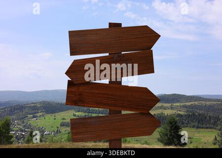 Panneau de signalisation en bois avec des flèches pointant dans différentes directions dans les montagnes Banque D'Images