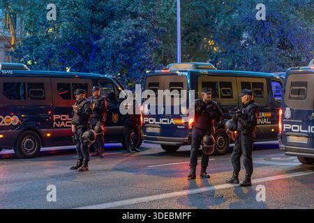 Des officiers de la police nationale espagnole en tenue anti-émeute se tiennent à côté de fourgonnettes lors d'une manifestation au crépuscule. Banque D'Images