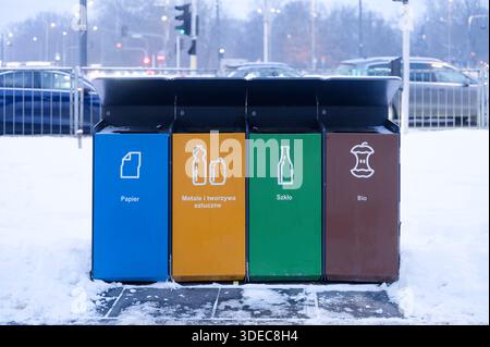 Bacs de recyclage publics colorés pour le papier, le plastique, le verre et les déchets bio debout dans un environnement urbain enneigé, concept de séparation des déchets. Banque D'Images