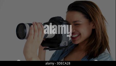 Tenant femme photographe portant une chemise en denim, visant DSLR avec téléobjectif blanc au studio Banque D'Images