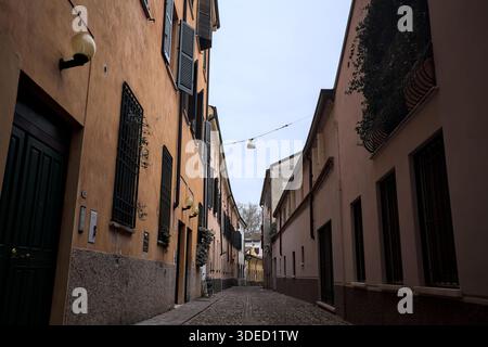 Étroite ruelle pavée avec des façades de bâtiments bas à l'ombre sur une journée nuageuse dans une ville italienne Banque D'Images