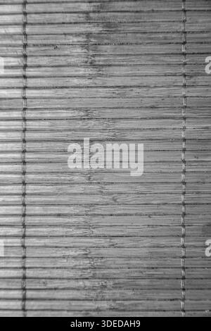 Texture noire et blanche d'un tapis de bambou naturel avec lattes horizontales et coutures verticales. Banque D'Images