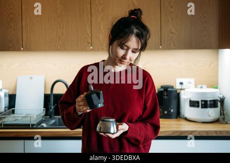 La personne assemble les composants du pot de moka dans la cuisine. Café artisanal, technique manuelle de l'espresso, rituel de café de spécialité, étapes de préparation du café. Banque D'Images
