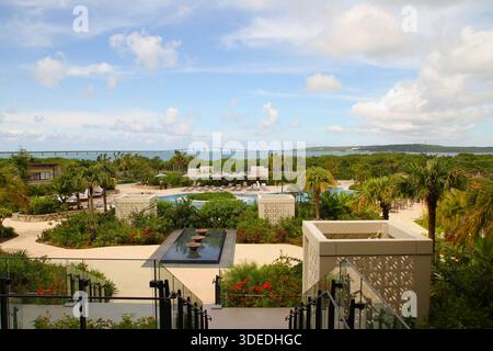 Architecture moderne de jardin et piscines au Hilton Okinawa Miyako Island Resort avec pont Irabu au loin, Okinawa, Japon. Banque D'Images