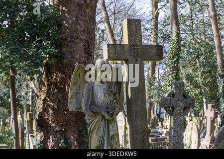 Statue d'ange en pierre et croix dans le cimetière historique, Londres, Royaume-Uni Banque D'Images