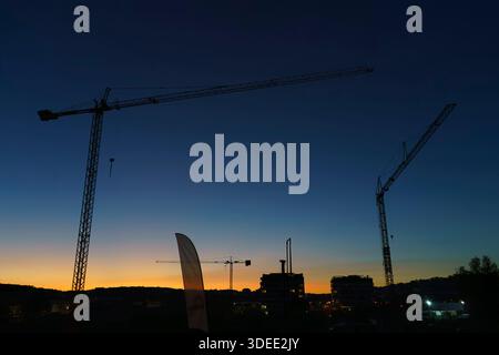 Silhouettes de grues de construction et de bâtiments au crépuscule avec un ciel crépusculaire clair en arrière-plan Banque D'Images