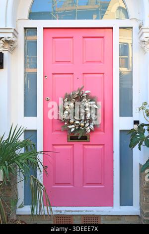 Couronne de Noël sur une porte d'entrée rose vif sur une maison victorienne dans le sud de Londres, Royaume-Uni. Banque D'Images