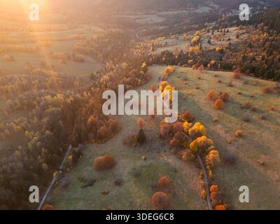 Vue aérienne de la lumière dorée se répand à travers les prairies et les forêts, peignant le paysage dans des teintes chaudes, Velka Ponicka dolina, Polana, Banska Bystrica Banque D'Images