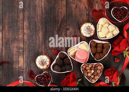 Nourriture pour la Saint-Valentin ou la Fête des femmes, bonbons au chocolat en forme de coeur gourmand, canneberge au sucre, meringue et fleurs de rose, carte de voeux, Adversin Banque D'Images