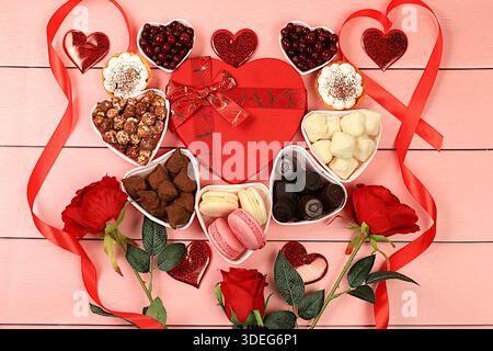 Bonbons gourmands au chocolat en forme de coeur, canneberge au sucre, meringue et fleurs de rose, nourriture pour la Saint-Valentin ou la Fête des femmes, carte de voeux, Adversin Banque D'Images