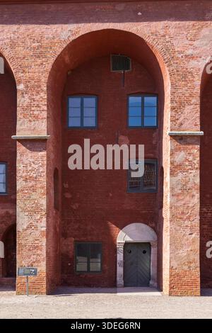 Charmante façade rose de la citadelle de Landskrona dans le sud de la Suède avec de grandes arches, des fenêtres à cadre bleu et une porte voûtée robuste, capturant le textu Banque D'Images