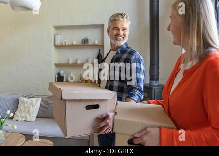 Homme et femme souriant tenant des boîtes dans le salon Banque D'Images