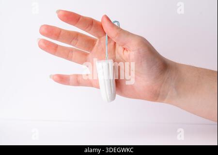 La personne tient un tampon à la main tout en se tenant debout dans une salle de bain. Banque D'Images