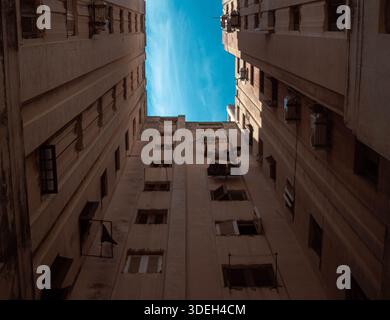 Vue verticale à faible angle de grands immeubles d'habitation altérés à la Havane, atteignant une étroite bande de ciel bleu. Densité et texture urbaines. Banque D'Images