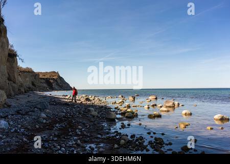 Un homme se balance sur des pierres le long de la côte de la mer Baltique près des falaises de Dornbusch sur l'île de Hiddensee, Mecklembourg-Poméranie occidentale, Allemagne Banque D'Images